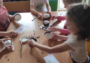 Dzieci przygotowują świeczniki z ziarenek kawy.